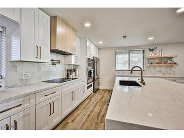 Modern kitchen featuring white cabinets, quartz countertops, stainless steel appliances, and a stylish island with seating at 9340 W Washburn Rd, Las Vegas, NV 89149