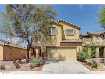 Charming two-story home showcasing a tan facade, complemented by a two car garage, desert landscaping, and shade tree at 952 Crescent Falls St, Henderson, NV 89011