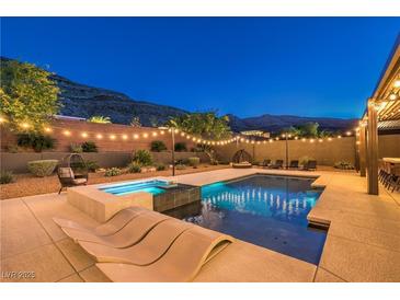 Inviting backyard features a sparkling pool, spa, lounge chairs and string lights for evening enjoyment at 10149 Terrastone Dr, Las Vegas, NV 89148