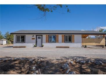 Charming single-story home with white siding, black trim, wood accents, and desert landscaping at 1050 Bruce St, Pahrump, NV 89048