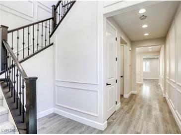 Bright hallway with wood floors, paneled walls, and a staircase with dark wood banister at 10164 Phelps Lake Ct, Las Vegas, NV 89148