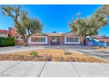 Charming single-story home with mature trees, desert landscaping, brick accents and a covered entrance at 1721 E Oakey Blvd, Las Vegas, NV 89104