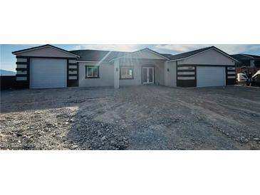 Charming single-story home with a symmetrical facade, featuring a gravel driveway and a two-car garage on each side at 1760 Omaha Ave, Pahrump, NV 89048