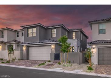 Two-story gray home boasts a brick driveway, manicured landscaping, and a spacious two-car garage at 2246 Bird Of Prey St, Las Vegas, NV 89138