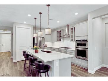 This kitchen features a large island with seating, stainless steel appliances and modern pendant lighting at 2386 Millergrove Ave, North Las Vegas, NV 89086