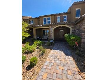 Charming townhouse with a stone-accented facade, covered porch, and a well-manicured front yard at 2497 Rofrano Pl, Henderson, NV 89044