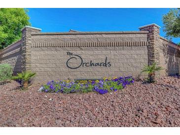 Stone sign at The Orchards community entrance with colorful flower beds and landscaping at 7380 Abundant Harvest Ave, Las Vegas, NV 89131