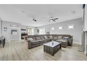 Spacious living room with comfortable sectional sofa, projector, and ceiling fan at 8836 Martin Downs Pl, Las Vegas, NV 89131