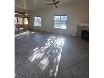 Bright living room featuring tile floors, large windows, and a cozy fireplace, perfect for comfortable living at 8985 S Durango Dr # 1154, Las Vegas, NV 89113