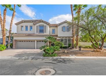 Two-story stucco home featuring a three-car garage, tile roof, and professionally landscaped yard with palm trees at 253 White Willow Ave, Las Vegas, NV 89123