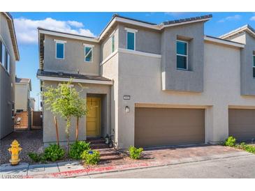 Charming townhome with a two-car garage, yellow front door and low-maintenance landscaping at 2691 Mango Light Ave, North Las Vegas, NV 89086
