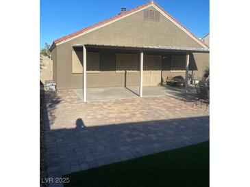 View of covered patio with brick pavers, privacy door, and outdoor grill at 3443 Citruscedar Way, North Las Vegas, NV 89032