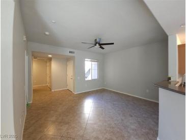 Bright, open living room featuring a ceiling fan and neutral tile flooring at 4675 Basilicata Ln # 103, North Las Vegas, NV 89084