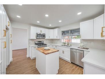 Bright kitchen features stainless steel appliances, white cabinets, quartz counters, and a butcher block island at 2107 Fountain Springs Dr, Henderson, NV 89074