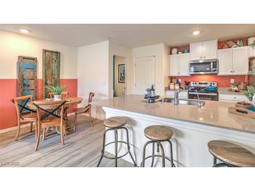 Bright kitchen features an island with bar seating, modern appliances, and a cozy dining area at 6918 Wrightshire St # 24, Las Vegas, NV 89166