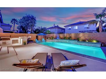Outdoor pool featuring water features, custom patio, and an outdoor kitchen area create a backyard oasis at 10902 Fintry Hills St, Las Vegas, NV 89141