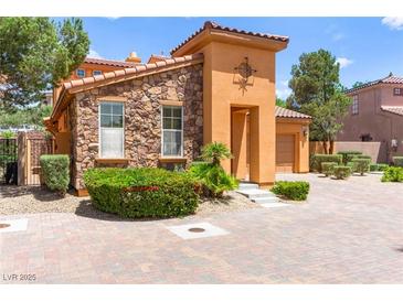 Charming home featuring stone and stucco exterior with a well-manicured front yard and a beautiful brick driveway at 1252 Casa Palermo Cir, Henderson, NV 89011