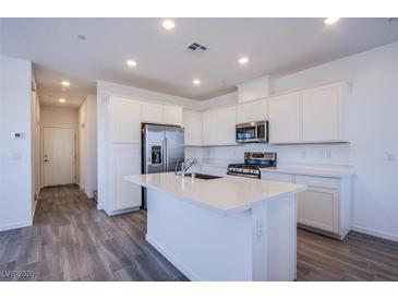 Bright kitchen features stainless steel appliances, an island, and plenty of white cabinets at 145 Aqua Commons Ln, Henderson, NV 89015