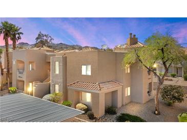 Tan stucco condo building featuring a tile roof, desert landscaping, and mountain views at 2200 Highpointe Dr # 202, Laughlin, NV 89029