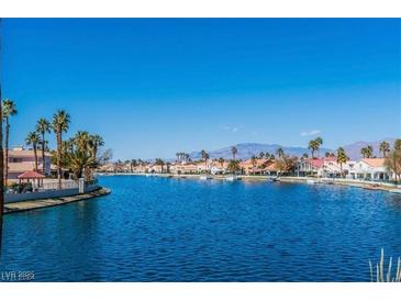 Scenic lake view featuring waterfront homes, palm trees, and mountain views in the distance on a bright, sunny day at 3151 Soaring Gulls Dr # 1023, Las Vegas, NV 89128