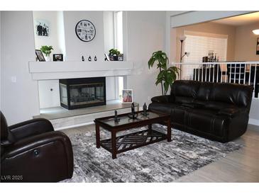 Cozy living room with a decorative fireplace, a dark leather couch, and a stylish area rug at 1680 Sweet Pea Ave, Las Vegas, NV 89183