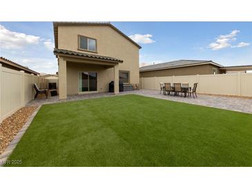 A well-manicured backyard boasts green artificial turf, a dining set, and a covered patio area at 2729 Pavehawk Way, Las Vegas, NV 89156