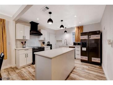 Bright kitchen featuring white cabinets, a large island, modern appliances, and stylish pendant lighting at 1414 S 13Th St, Las Vegas, NV 89104