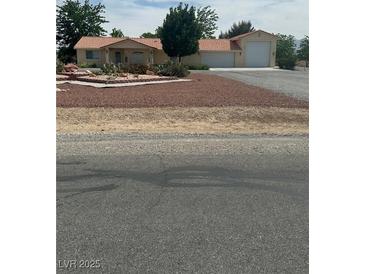 Charming single-story home featuring a terracotta roof, desert landscaping, and an attached two-car garage at 1461 E Elderberry St, Pahrump, NV 89048