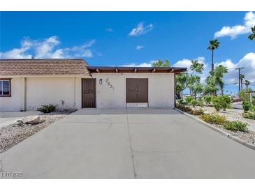 Tan single-story home with simple landscaping and a concrete driveway under a partly cloudy sky at 2635 Heritage Ct, Las Vegas, NV 89121