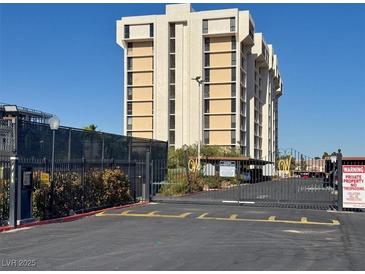 View of the condo building with a secured gate entrance and manicured landscaping under a clear sky at 3930 University Center Dr # 603, Las Vegas, NV 89119