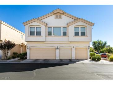 Inviting townhouse featuring a three-car garage and cream-colored facade under a clear blue sky at 6549 Clara Bow Ave # 103, Las Vegas, NV 89122