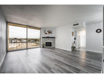 Bright living room featuring a stone fireplace, large windows with city views, and stylish gray wood flooring at 745 N Royal Crest Cir # 141, Las Vegas, NV 89169