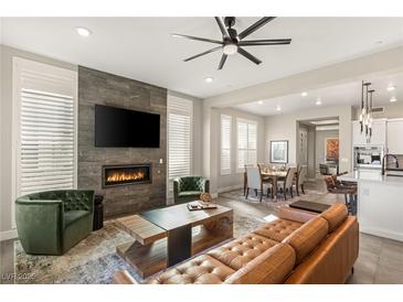 Open-concept living room with stone fireplace, flatscreen TV, and modern furnishings, seamlessly flowing into the dining area at 11280 Granite Ridge Dr # 1012, Las Vegas, NV 89135