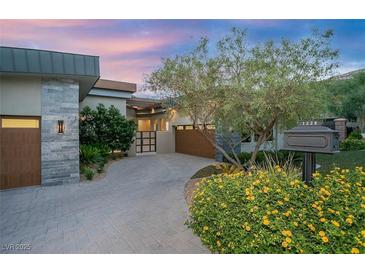 Stunning single story exterior with a circular driveway, lush desert landscaping and natural stone accents at 1228 Stellar Rim Ct, Henderson, NV 89012