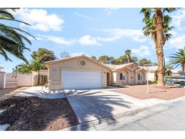 Single-story home showcasing a well-maintained yard, complemented by mature palm trees and attached two-car garage at 3145 Tarpon Dr, Las Vegas, NV 89120