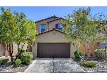 Inviting two-story home with a well-manicured lawn and a two-car garage, embraced by mature trees at 8739 Cerrito Canyon Ct, Las Vegas, NV 89148