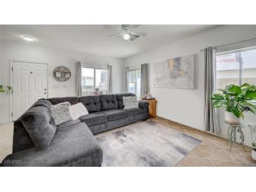 Inviting living room with tile floors, a comfortable gray sectional sofa and bright natural light from the windows at 8801 Duncan Barrel Ave # 103, Las Vegas, NV 89178