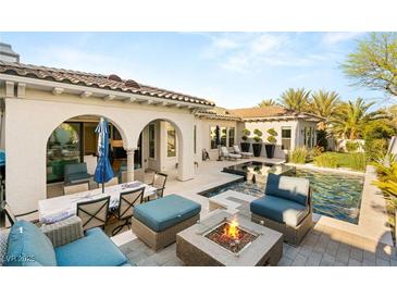 An inviting backyard oasis features a pool, spa, and outdoor seating around a cozy fire pit at 10717 Beringer Dr, Las Vegas, NV 89144