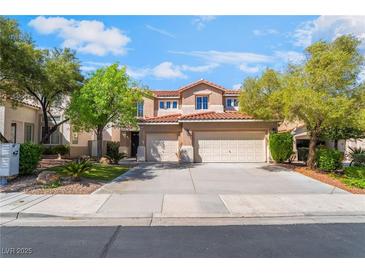 Charming two-story home featuring a red tile roof, spacious driveway, and lush landscaping at 1553 Ravanusa Dr, Henderson, NV 89052