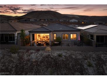 Charming home exterior with a cozy patio and mountain views at twilight at 174 Cabo Cruces Dr, Henderson, NV 89011