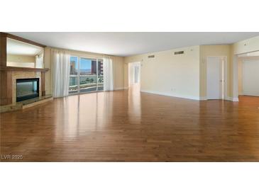 Spacious living room featuring hardwood floors, a fireplace, and sliding glass doors to the balcony at 2857 Paradise Rd # 802, Las Vegas, NV 89109