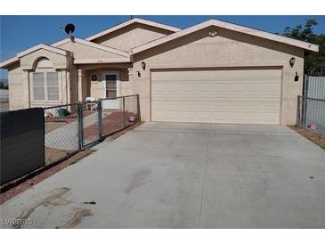 Single story home with two car garage, desert landscaping and chain link fence at 2920 Malibou Ave, Pahrump, NV 89048