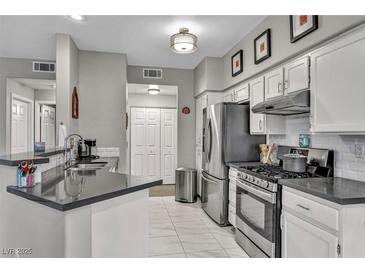 Bright kitchen features stainless steel appliances, grey countertops, and white tile flooring at 8501 W University Ave # 1083, Las Vegas, NV 89147