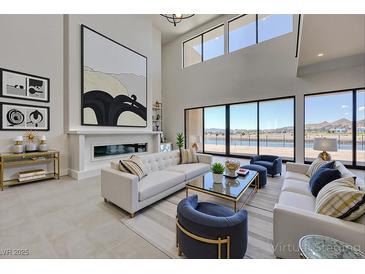 Bright living room boasts high ceilings, modern fireplace, and expansive windows with lake views at 1600 Pleasant Bay Ct, Henderson, NV 89011