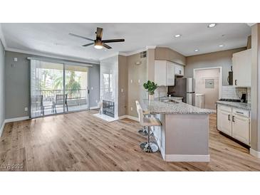 Open living space boasts hard wood flooring, a ceiling fan, fireplace, and a sliding glass door to the patio at 7173 S Durango Dr # 307, Las Vegas, NV 89113