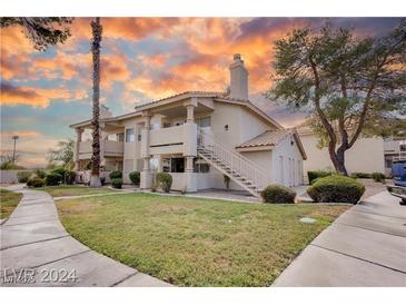 Inviting two-story condo with well-maintained landscaping and warm exterior lighting at sunset at 1300 Pinto Rock Ln # 201, Las Vegas, NV 89128