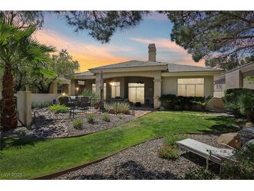 Beautiful backyard featuring lush landscaping, patio with seating, and a serene outdoor space at 304 Cambrian Ridge Ct, Las Vegas, NV 89144
