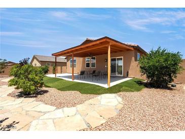 Beautiful backyard featuring a covered patio, landscaped yard, and decorative stone pathway at 3543 E Malheur Ave, Pahrump, NV 89061