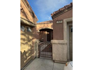 Charming home features an arched porch, metal gate, and desert landscaping at 3928 Ropers Ranch St, North Las Vegas, NV 89032