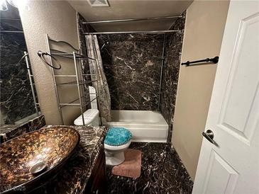 Bathroom with marble-style wall covering, single sink, and shower over tub at 5188 River Glen Dr # 453, Las Vegas, NV 89103